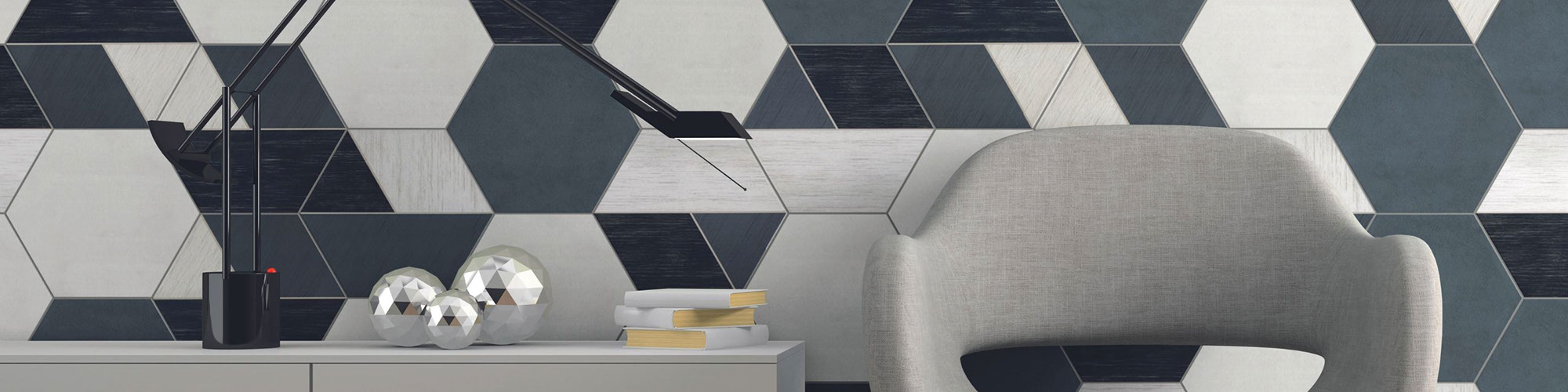 Eye-catching feature wall with white, gray and black hexagon tile, gray chair, gray credenza holding desk lamp and books, and gray floor tile.
