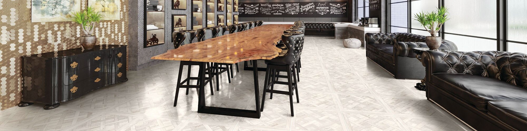 Industrial conference room with cassettone pattern floor tile that looks like white-washed wood, raw edge long table with leather chairs, and leather couches.