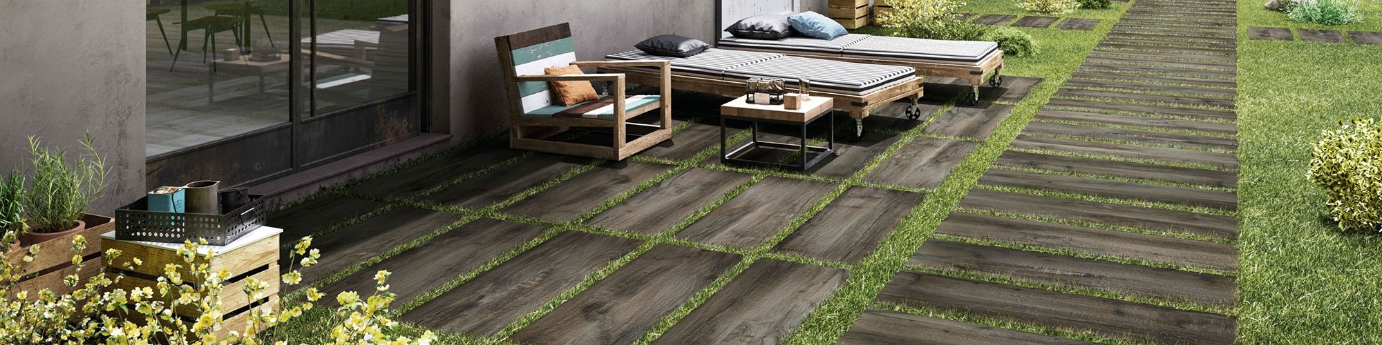 Lawn furniture on 16" x 48" 2 centimeter porcelain pavers that look like seasoned wood planks, set in green grass.