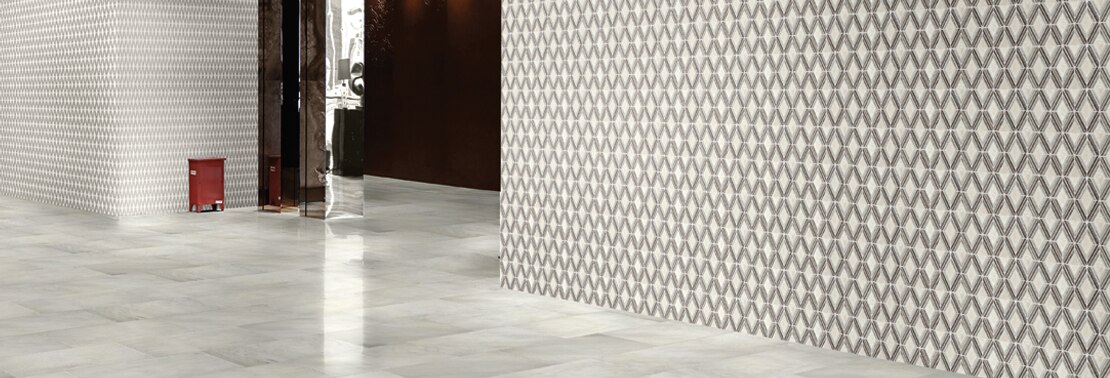 Luxurious hotel lobby with large-format white/gray marble floor tile, white & gray diamond-shaped marble mosaic wall tile, and mirrored elevator doors.