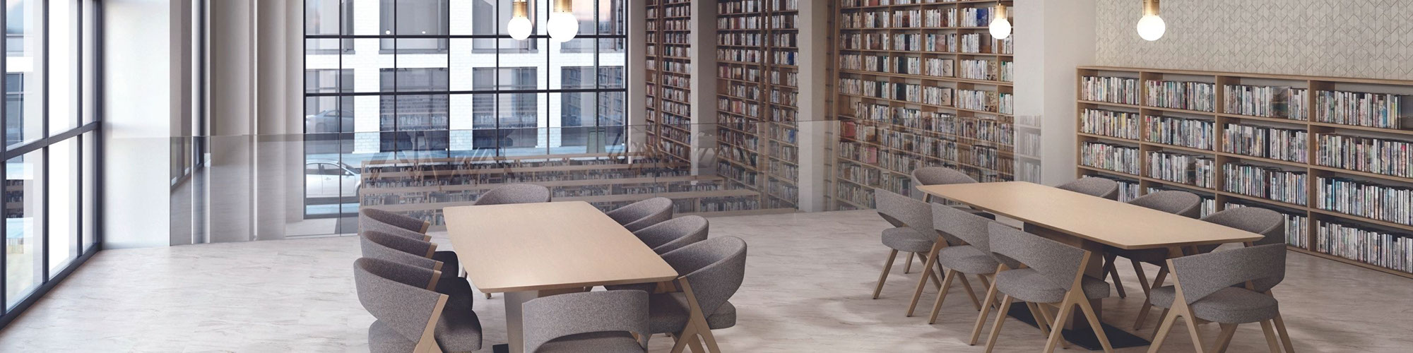 Public library with marble look tile floor, table & chairs, bookshelves, chevron wall tile, pendant lights, and floor-to-ceiling windows.