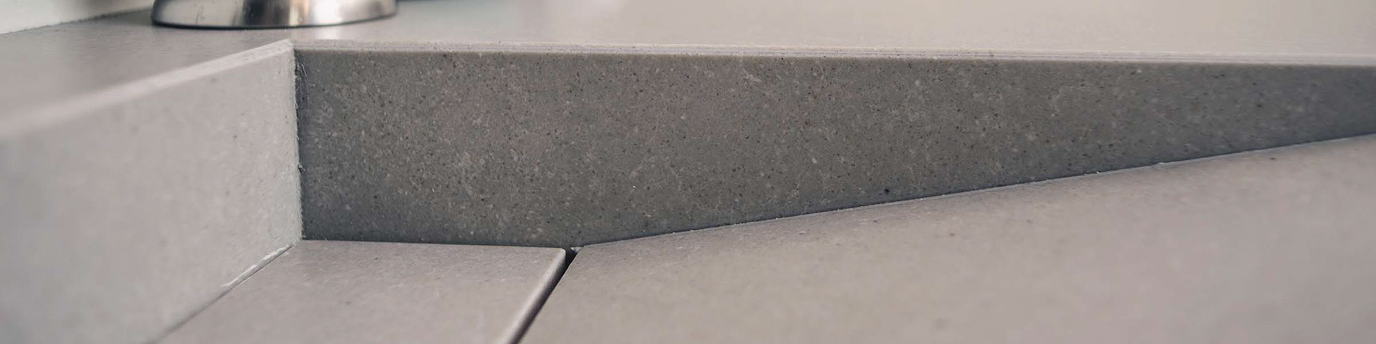 Closeup of gray quartz bathroom vanity and sink that looks like concrete.