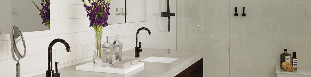Bathroom with white subway tile backsplash, vanity with double sinks, gray quartz countertop and black cabinets, and shower with gray quartz slab walls and bench.