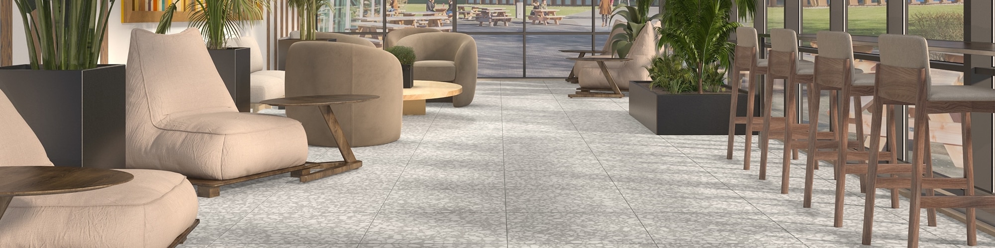Student center sunroom with gray floor tile that looks like terrazzo, beige over-stuffed chairs with side tables, and beige barstools facing ceiling-to-floor windows.
