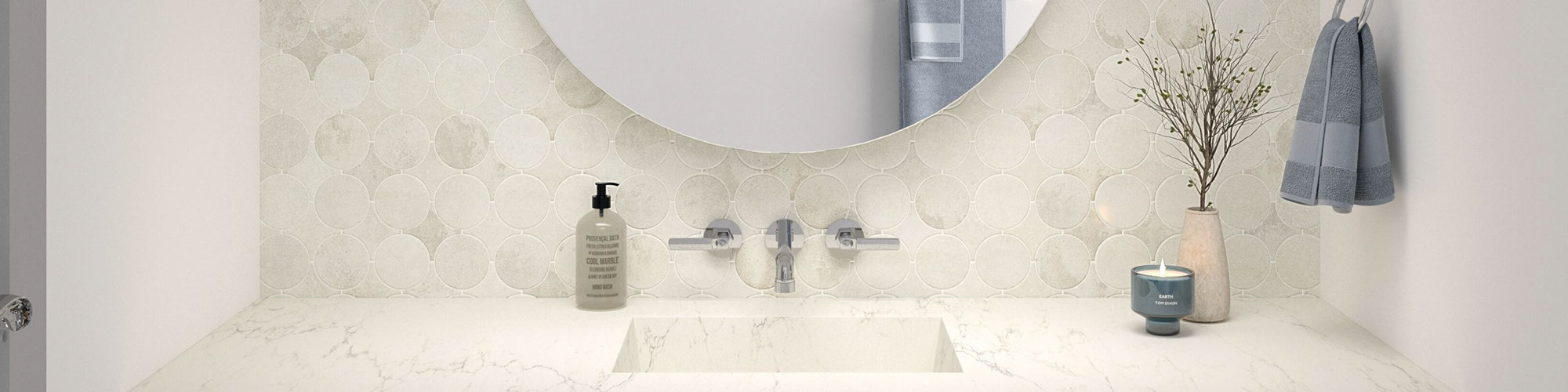 Bathroom vanity with white & gray canvas dot tile backsplash and quartz countertop, both look like marble, wall-mounted faucet, and round mirror.