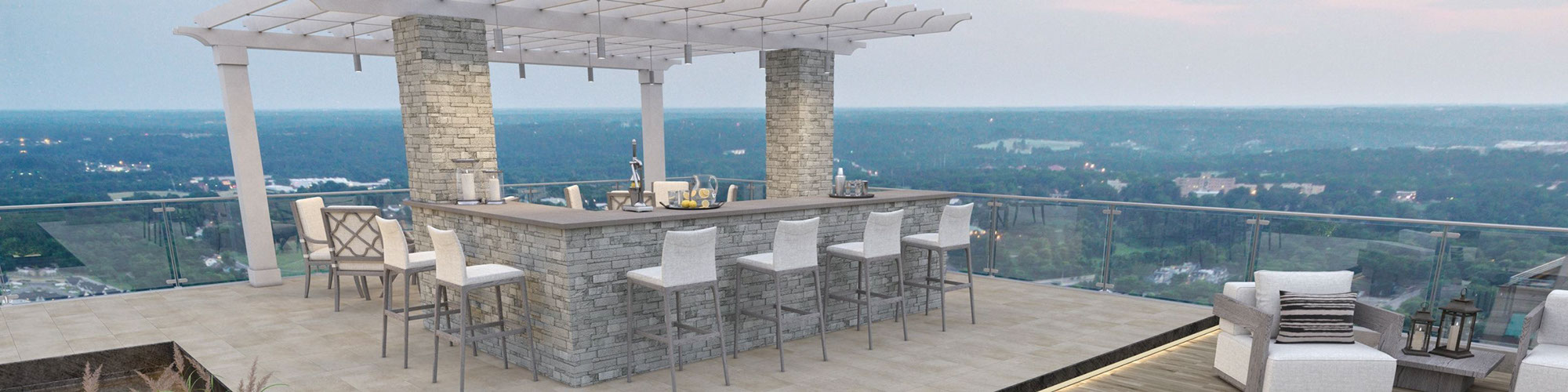 Rooftop patio with stacked stone-faced bar under a pergola, wood look slip-resistant floor tile, and gray paver walkway set in grass.