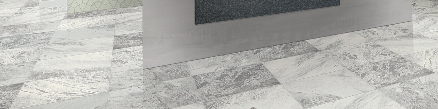 Closeup of 12x24 white & gray marble tile floor in office building lobby.