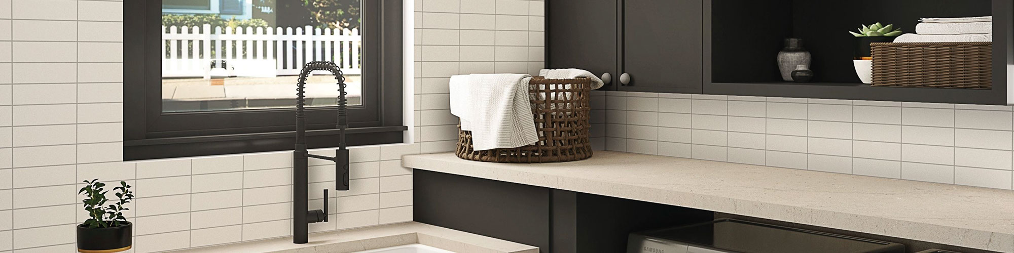 Laundry room with sink, black matte faucet, off-white quartz counters, off-white subway wall tile in grid pattern, and open brown cabinets.