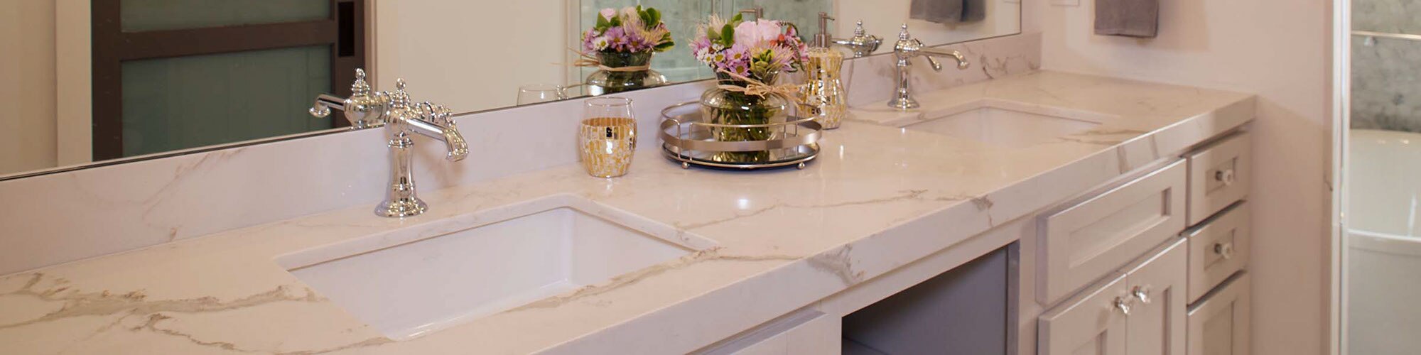 Bathroom with white marble-look quartz countertop, dual under-mount sinks, polished silver faucets, and white cabinets.