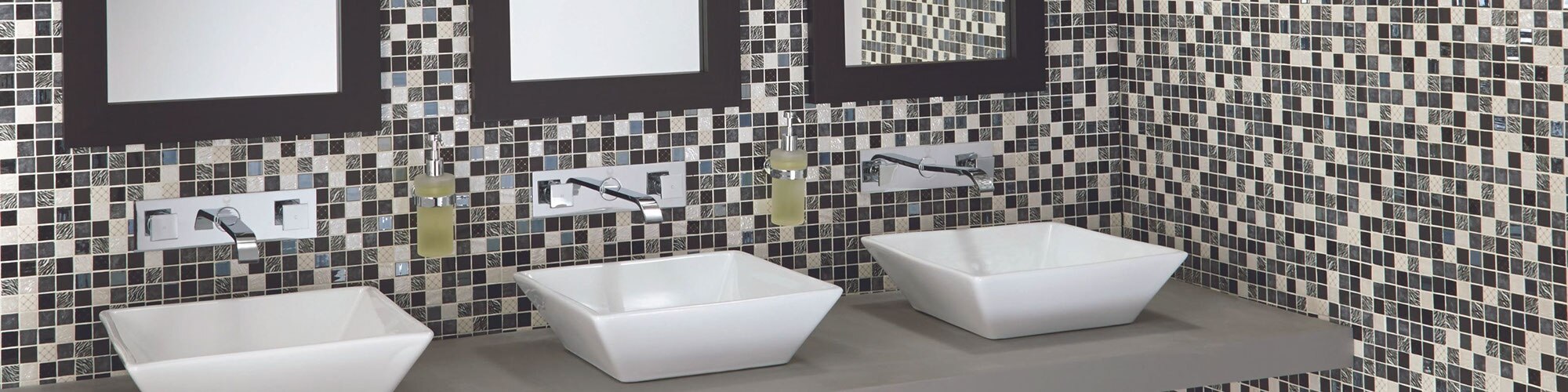 Restaurant bathroom with off-white, gray, and brown glass mosaic backsplash, polished silver wall mounted faucet, 3 white vessel sinks on gray floating vanity.