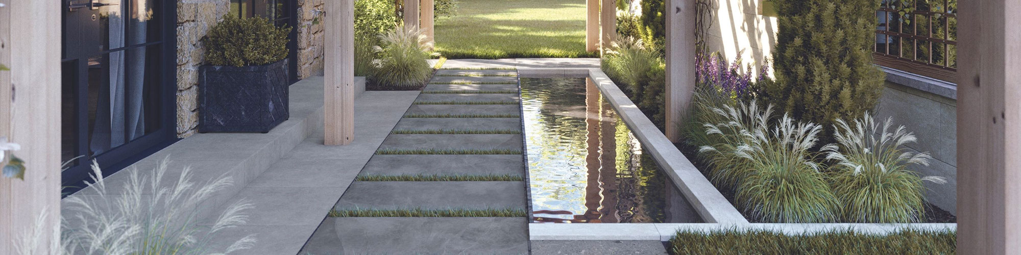 Close up of residential outdoor courtyard walkway of porcelain paver tiles set in grass, next to a coy pond.