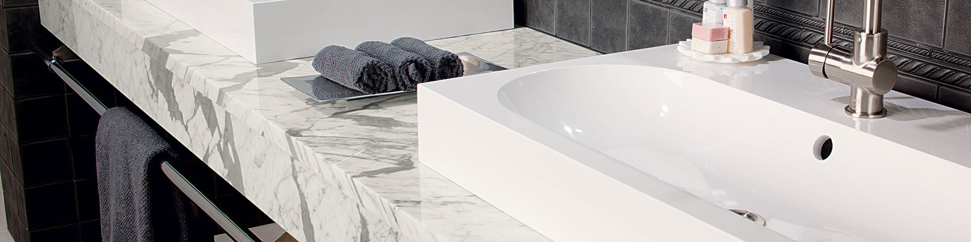 Close up of white with gray veined marble bathroom vanity countertop with dual vessel sinks.