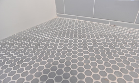 Closeup of gray penny round shower floor tile with white grout.