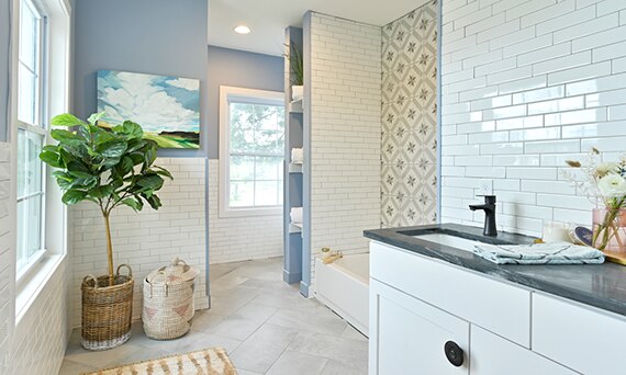 Bathroom with black soapstone vanity countertop, white subway backsplash, gray encaustic shower tile, and gray metal look floor tile.