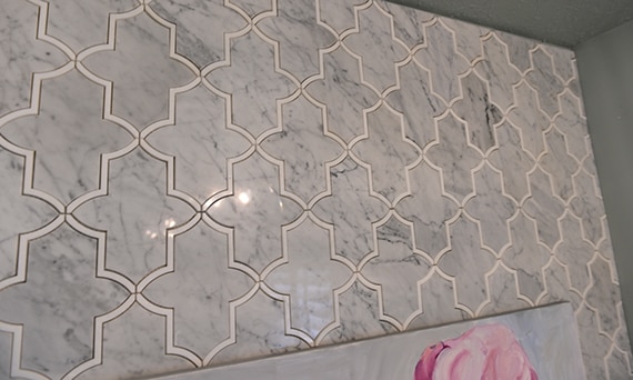Closeup of pantry wall with mosaic gray marble tile with white marble accents.