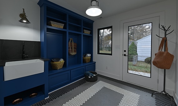 Mudroom with blue cubbies, farm sink with black quartz backsplash, white, gray & black hex mosaic floor tile, and door with window.