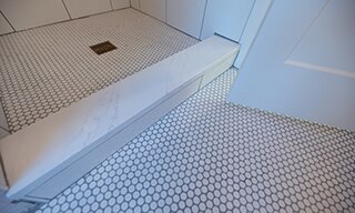 Closeup of white penny round floor tile and shower floor tile.