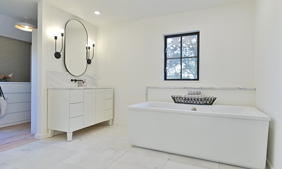 Bathroom with vanity of white & gray marble countertop, white marble tile floor, freestanding bathtub with white quartz & marble trim backsplash.