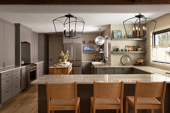 Kitchen with gray pantry shelves and cabinets, with a beige quartzite countertop, white concrete look subway tile on the walls, and yellow mosaic tile on cabinet backsplash.