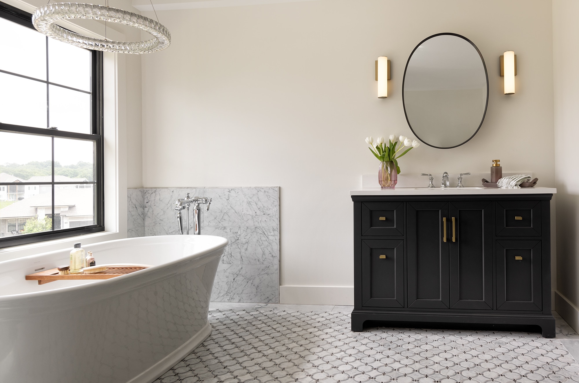 Bathroom with a black cabinet, white bathtub, white ring mosaic on the floor and a white marble slab surrounding the tub.