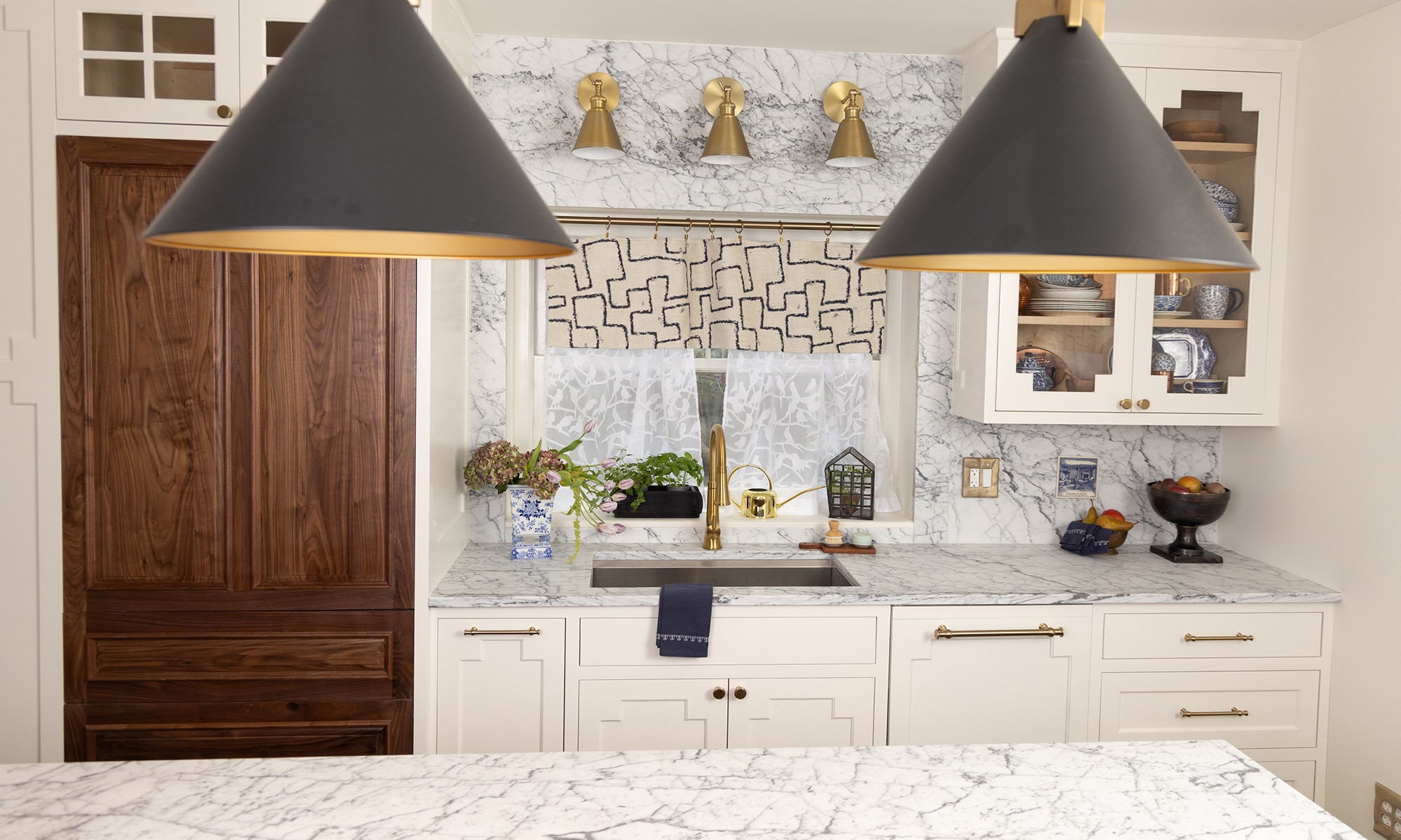 Kitchen with sink and window, white cabinets, dark wood cabinets on the pantry, and white marble countertops and backsplash