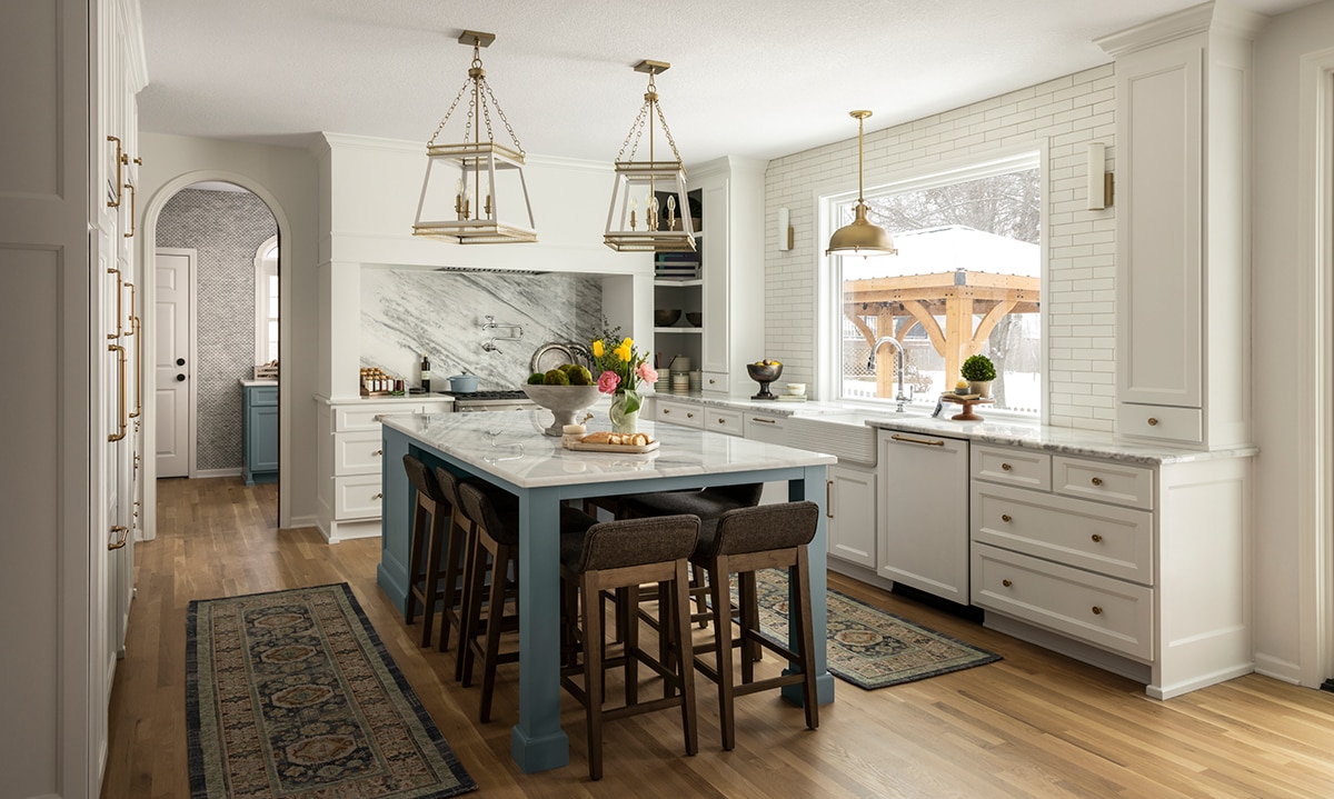 Kitchen with white cabinets. center island, and a white marble slab countertop and backsplash.