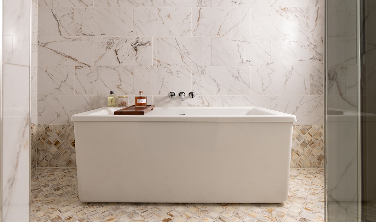 Bathroom with white marble look mosaic on the floor and bottom half of the wall, and white marble look rectangle tile on the top half of the wall.