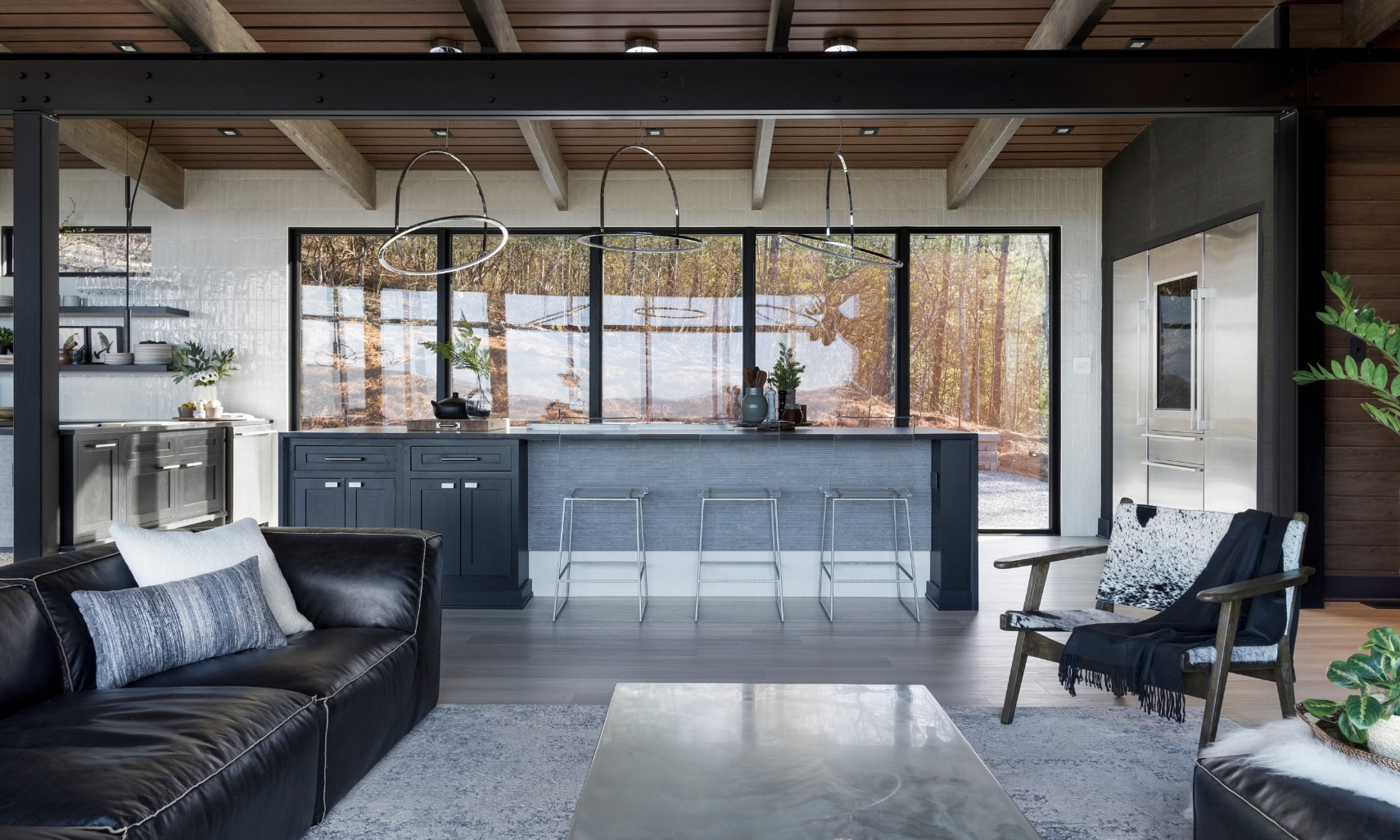 Chip Wade’s residential renovation, Pinhoti Peak, open kitchen, dining room, living room with black quartz countertops, white glossy wall tile, and floor-to-ceiling windows.