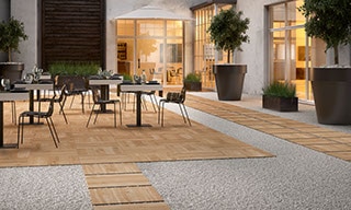 Outdoor hotel restaurant with 24” x 24” 2 centimeter porcelain pavers that look like elm wood for dining area flooring and walkway set in gravel.