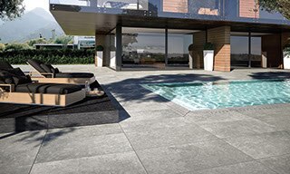 Backyard of two-story house with floor-to-ceiling windows, natural wood shiplap siding, and pool with gray stone look pavers.