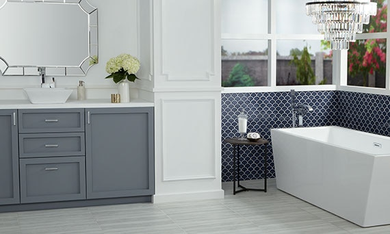 Large bathroom with large windows, soaker tub, grey vanity, with blue fish scale mosaic tile on the wall.
