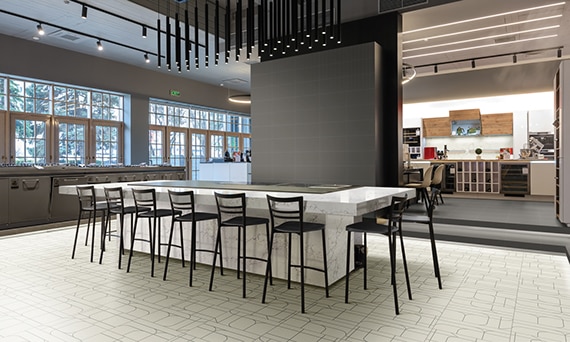 Hibachi restaurant with beige tile flooring with gray designs, gray wall tile, white & gray quartz table with grill and black metal chairs. 