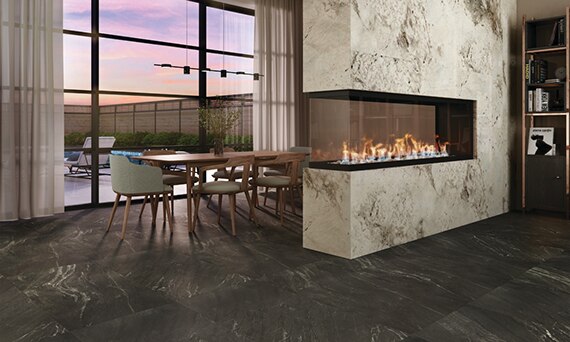 Modern dining room with black marble look tile flooring, open fireplace with cream & brown granite surround, table & chairs in front of glass sliding doors.