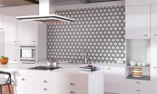 Modern kitchen with black & white hexagon backsplash, white countertop, white cabinets, island with glass stove top & hood vent.