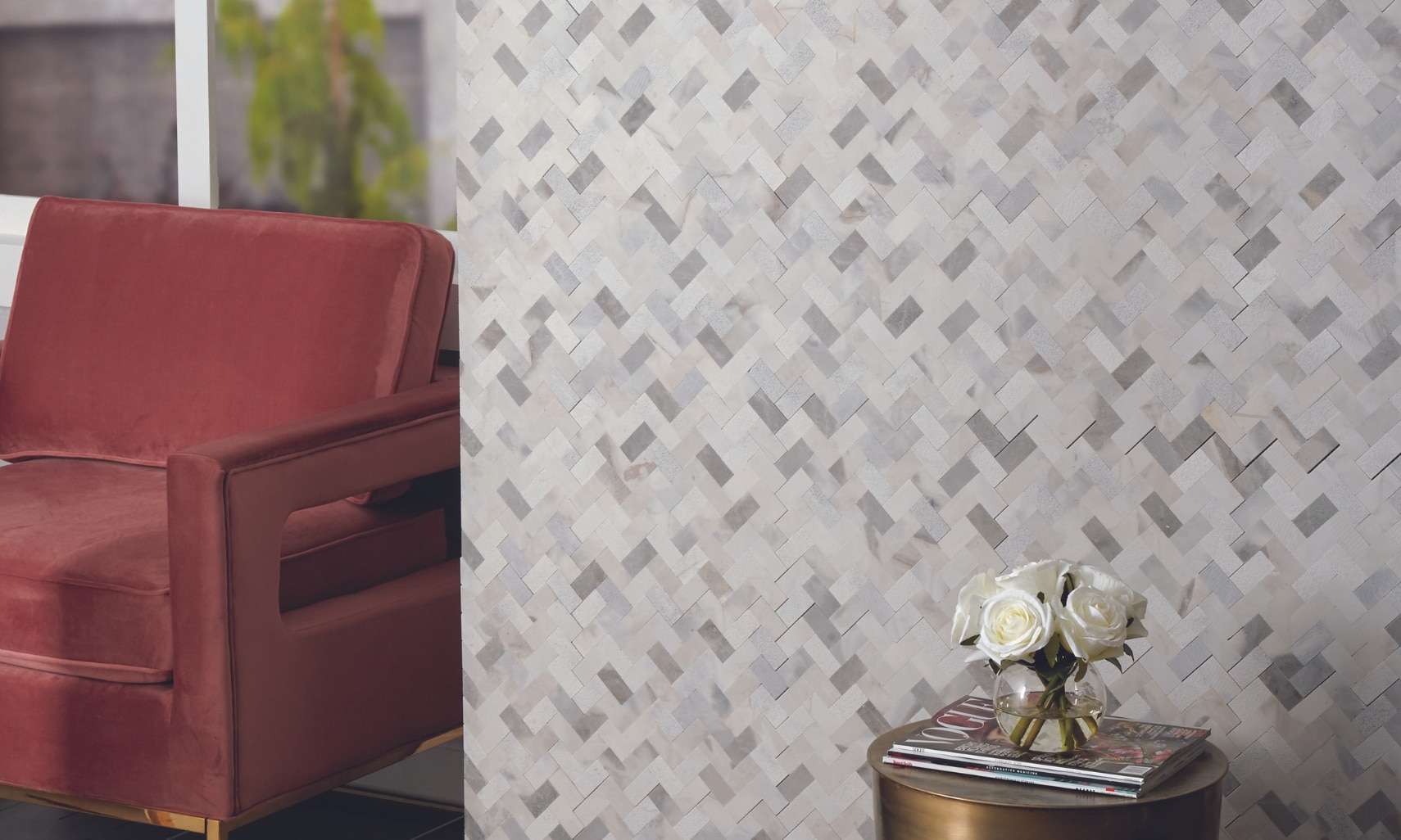 Groutless mosaics: White, gray and beige marble mosaic wall that does not require grout, red velvet chair, and side table holding white roses.