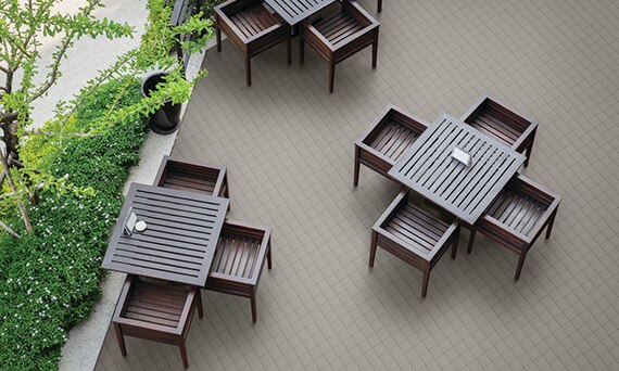 Bird’s eye view of outdoor restaurant with gray 6x6 quarry tile flooring, wood table and chairs, and patio surrounded by shrubs.