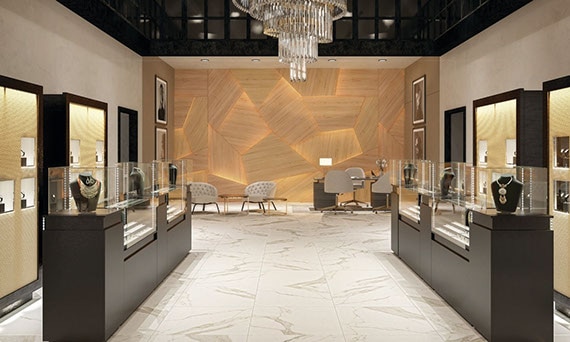 Fine jewelry store with off-white and gray large format floor tile, jewelry in glass cases, crystal and brass chandelier, and woodgrain wall with embedded lighting.