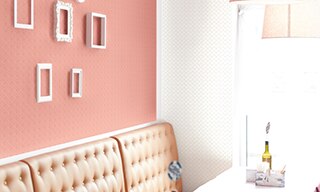 Restaurant booth next to window with peach leather seatback, white mosaic wall tile, and white picture frames on peach mosaic wall tile.