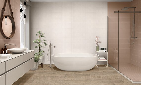 Bathroom with tan stone look floor tile, soaker tub in front of wall of white textured tile, separate shower with mauve tile and frameless glass doors.