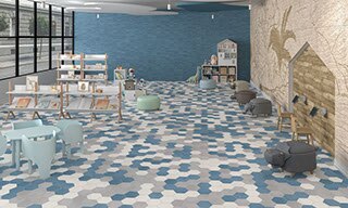 Children’s playroom with blue, white, and gray hexagon floor tile, blue wall tile, mural, bookshelves, dollhouse, child-size table & chairs and ottomans.