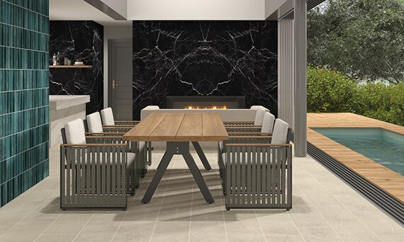 Dining room with beige stone look floor tile, aqua wall tile, black marble look porcelain fireplace surround, table & chairs, bifold glass doors open to backyard pool.