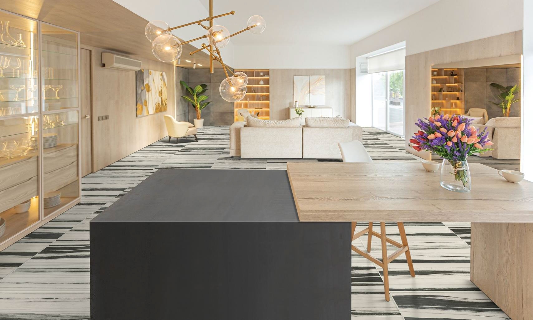 Open contemporary kitchen / living / dining room with white and black floor tile & wood panel walls, black metallic waterfall & butcher block island counter.