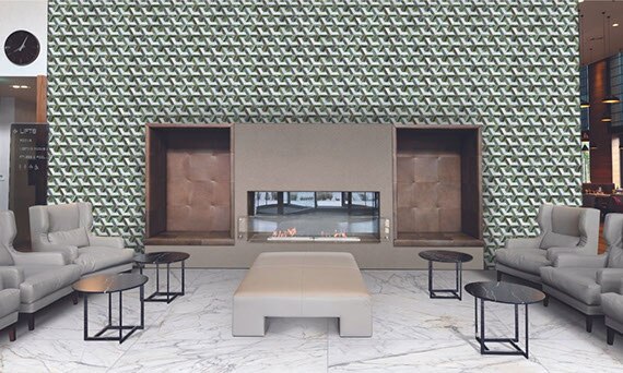 Hotel lounge area with green and white glass mosaic tile feature wall with electric fireplace, white & gray marble-look floor tile, and leather chairs & ottoman.
