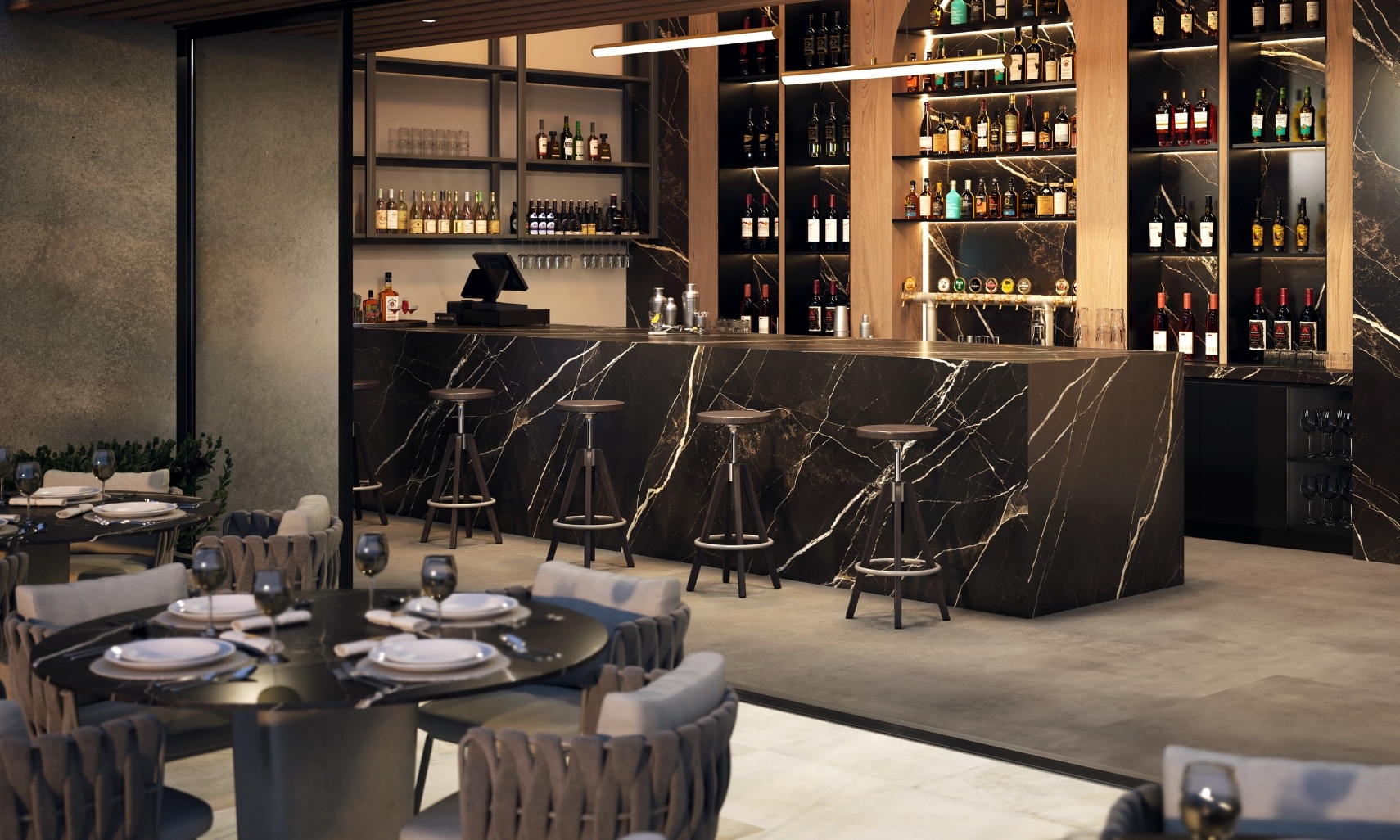 Restaurant patio and bar with black & white veining porcelain slab waterfall countertop and backsplash, gray concrete look floor tile, table and chairs.