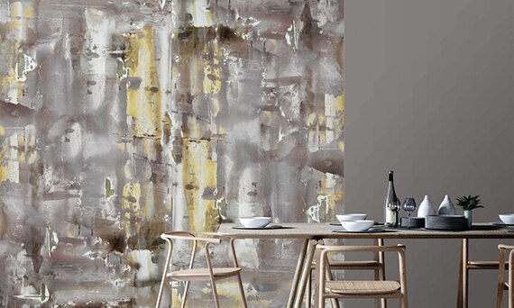 Dining room with table & chair in front of feature wall of gray, white, and yellow porcelain slab with abstract design.
