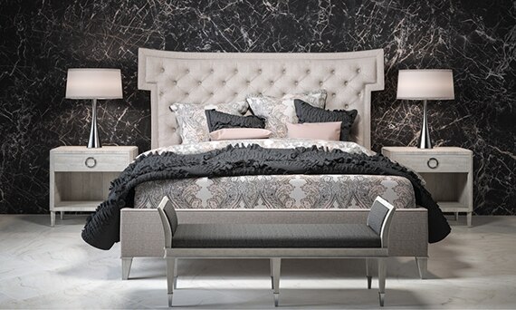 Elegant bedroom with white, gray & tan marble look tile flooring, feature wall with black & white marble look, porcelain slab, and cushioned headboard on king-sized bed.