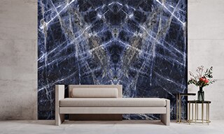 Lobby with beige marble-looking slab flooring and walls, tan chaise lounge and side table in front of large dark blue bookmatched marble-look slab with gray & white striations.