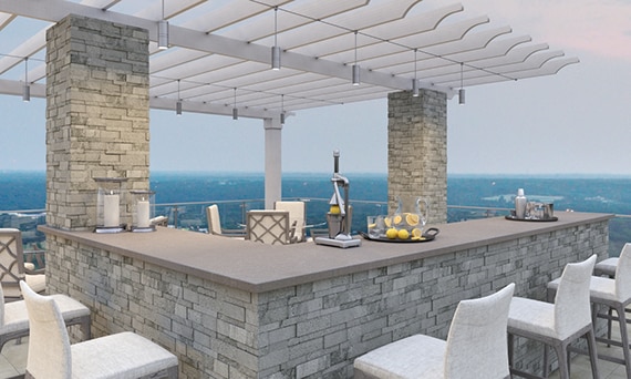 Rooftop patio with gray porcelain slab countertops, gray stacked stone-faced bar under a pergola, white linen bar stools.