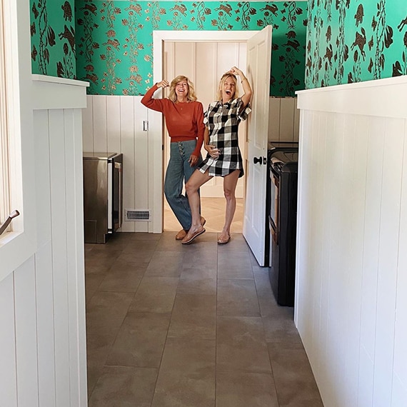 Newly renovated laundry room with gray floor tile that looks like concrete, green wallpaper with gold foil bunnies, and white shiplap wainscot.
