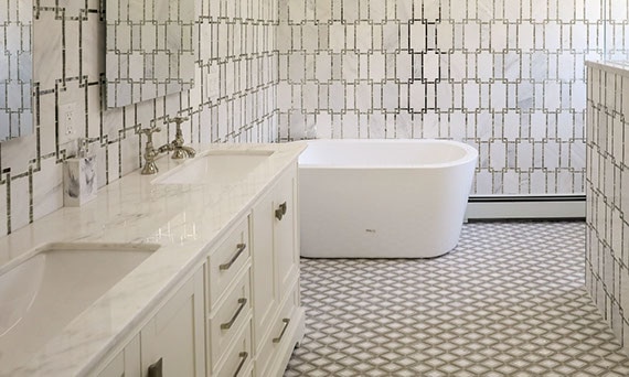 Bathroom with white marble & antique mirror wall tile, white marble vanity countertop, white & gray diamond-shaped mosaic floor tile, and soaker tub.